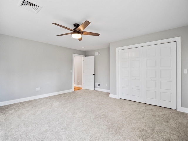 unfurnished bedroom featuring ceiling fan, a closet, and light carpet