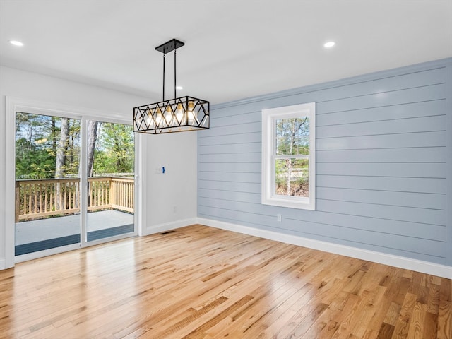 unfurnished dining area with wood walls and light hardwood / wood-style floors