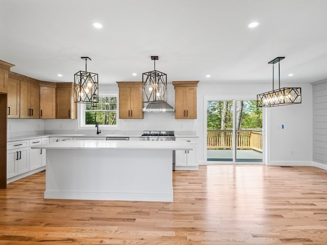 kitchen with a kitchen island, hanging light fixtures, light hardwood / wood-style floors, and white cabinetry