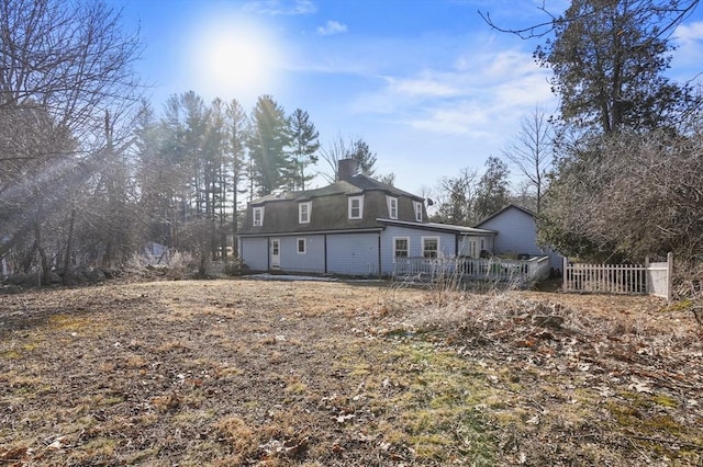 back of property with a chimney and fence