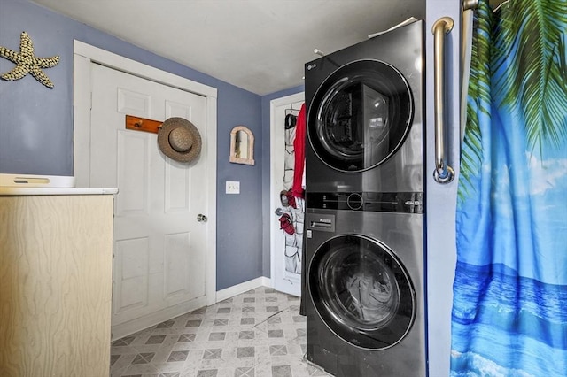 laundry room with light floors, stacked washer and clothes dryer, and baseboards