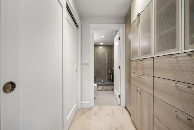 hall featuring light wood-style flooring, baseboards, and recessed lighting