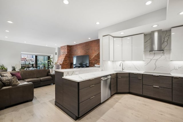 kitchen featuring wall chimney exhaust hood, modern cabinets, open floor plan, a peninsula, and white cabinetry