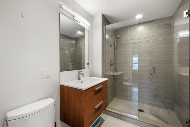 bathroom featuring toilet, a shower stall, vanity, and tile patterned floors
