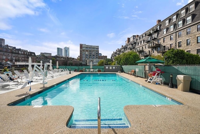 community pool with fence and a patio area