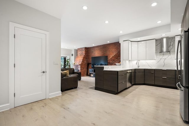 kitchen featuring wall chimney exhaust hood, modern cabinets, stainless steel appliances, white cabinets, and open floor plan