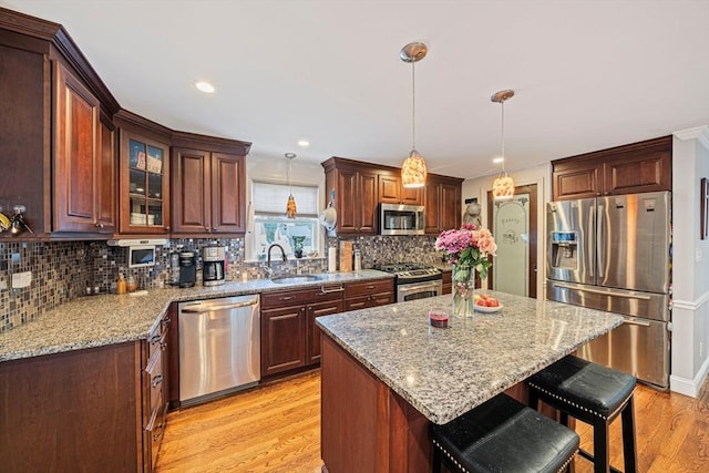 57 Century Rd, Weymouth, MA 02190 - kitchen featuring appliances with stainless steel finishes, a sink, light wood-type flooring, a breakfast bar area, and backsplash