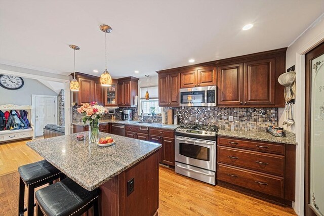 57 Century Rd, Weymouth, MA 02190 - kitchen with stainless steel appliances, a sink, a kitchen bar, backsplash, and light stone countertops