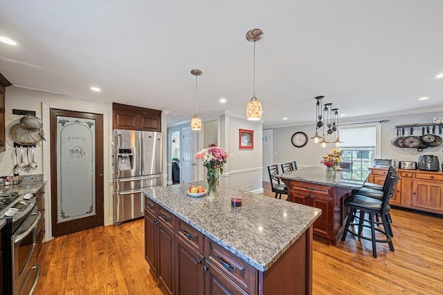 57 Century Rd, Weymouth, MA 02190 - kitchen with appliances with stainless steel finishes, a center island, crown molding, a kitchen breakfast bar, and recessed lighting
