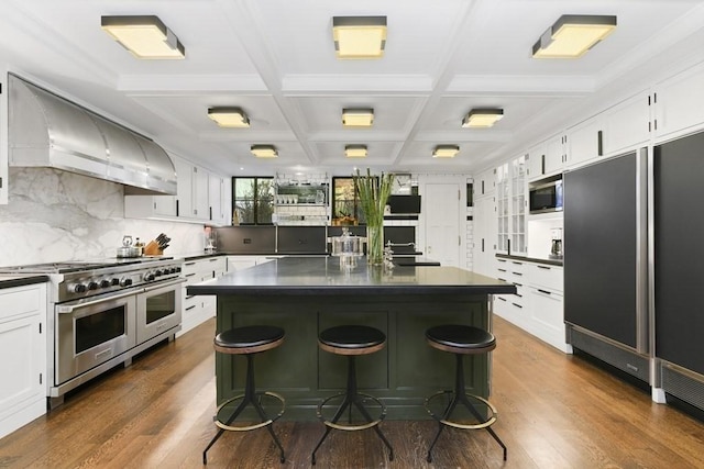 kitchen featuring built in appliances, premium range hood, dark countertops, and a center island