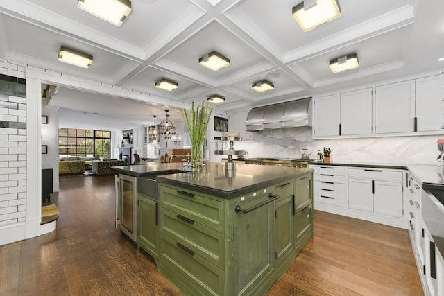 kitchen with white cabinets, dark countertops, wall chimney exhaust hood, a kitchen island, and green cabinetry