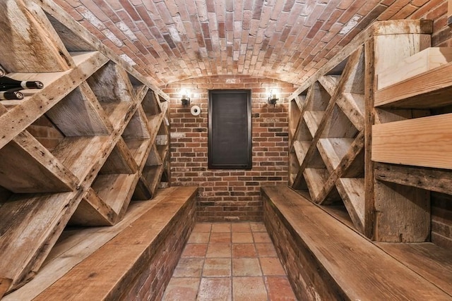 wine cellar featuring brick ceiling, brick wall, vaulted ceiling, and stone tile flooring