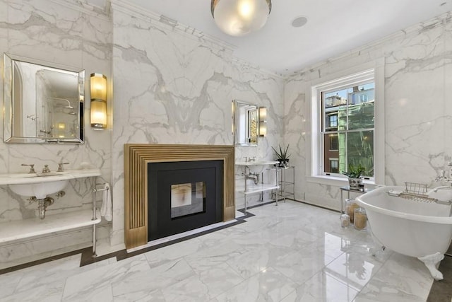 full bathroom with marble finish floor, stone wall, a soaking tub, and a glass covered fireplace