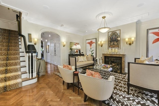 living area with arched walkways, ornamental molding, a premium fireplace, and stairway