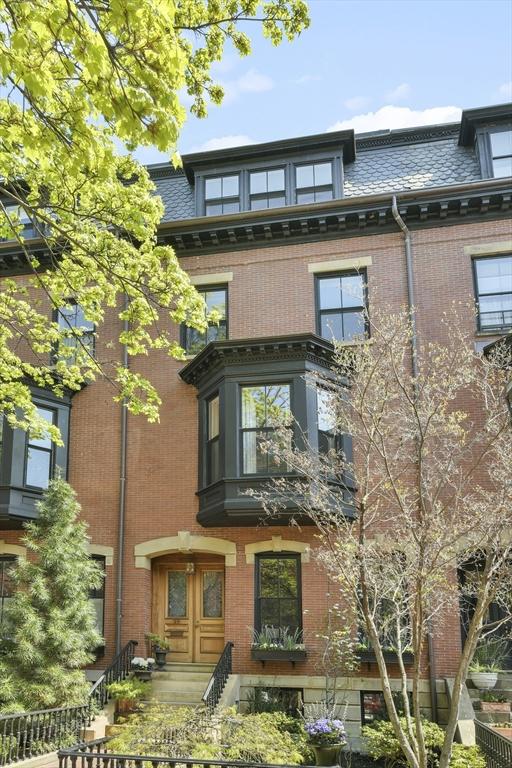 exterior space featuring brick siding, roof with shingles, and mansard roof