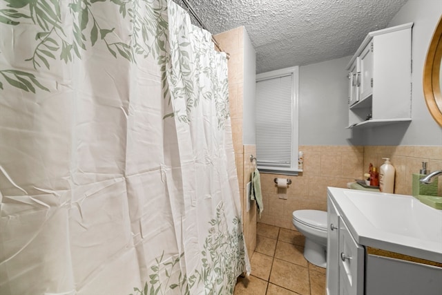 bathroom featuring vanity, tile walls, tile patterned flooring, toilet, and a textured ceiling