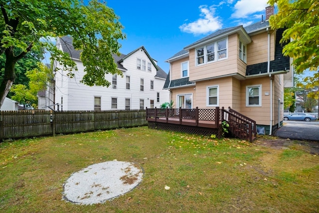 back of house with a deck and a lawn