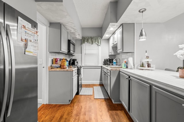 kitchen featuring sink, gray cabinets, appliances with stainless steel finishes, light wood-type flooring, and decorative backsplash