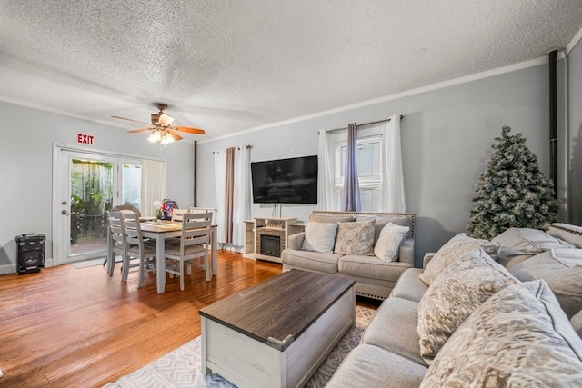 living room with ceiling fan, a textured ceiling, crown molding, and hardwood / wood-style floors