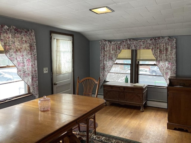 dining space with lofted ceiling, light wood-type flooring, and baseboard heating