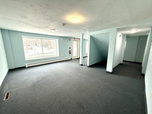 unfurnished room with a textured ceiling, a baseboard heating unit, and dark colored carpet