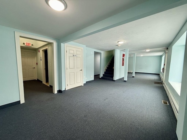 unfurnished room with dark carpet and a baseboard heating unit