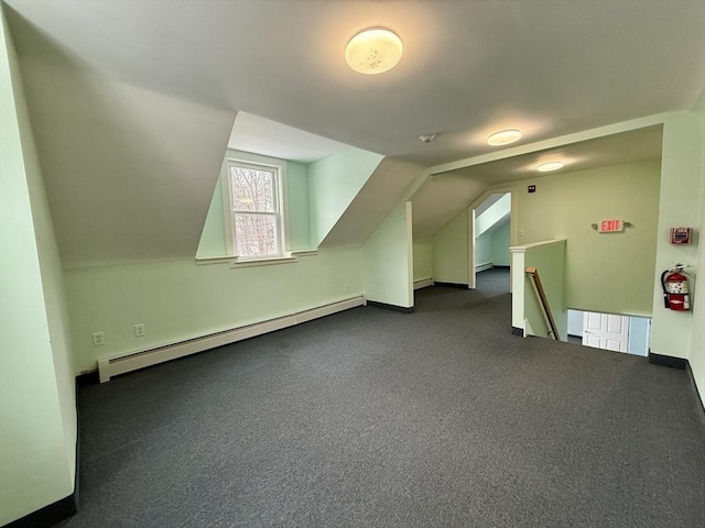 additional living space featuring baseboard heating, lofted ceiling, and dark colored carpet