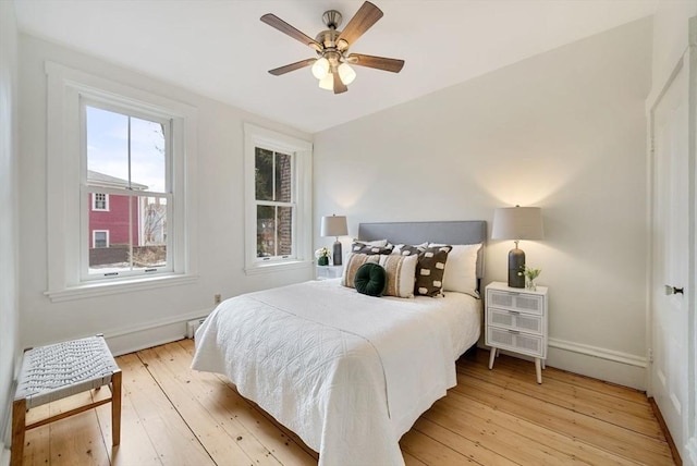 bedroom featuring light wood-style flooring, baseboards, and a ceiling fan