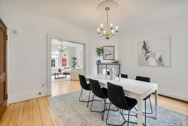 dining space with a chandelier, light wood-type flooring, baseboards, and crown molding