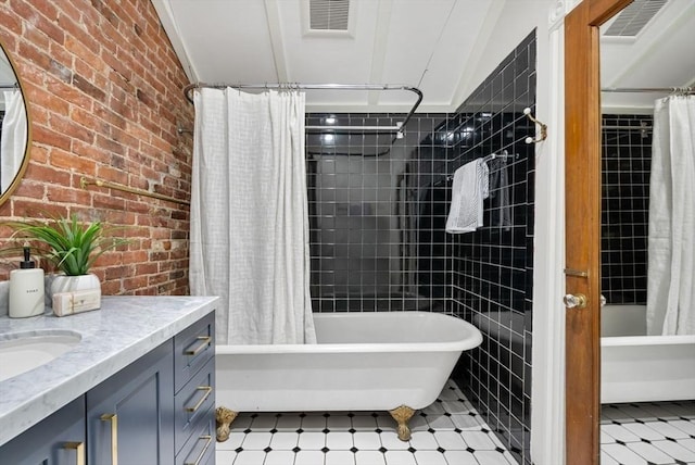 full bathroom with tile patterned floors, brick wall, shower / tub combo with curtain, and vanity