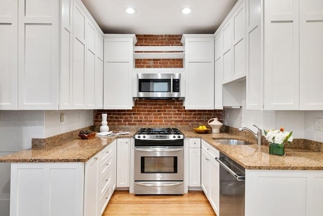 kitchen featuring stainless steel appliances, white cabinetry, a sink, and backsplash