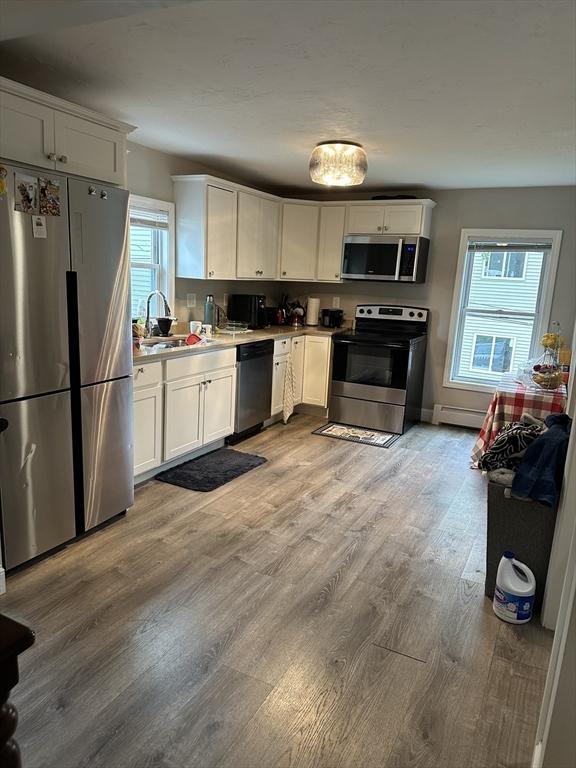 21 Sigel St, Worcester, MA 01610 - kitchen with appliances with stainless steel finishes, a sink, light wood-style floors, and white cabinets