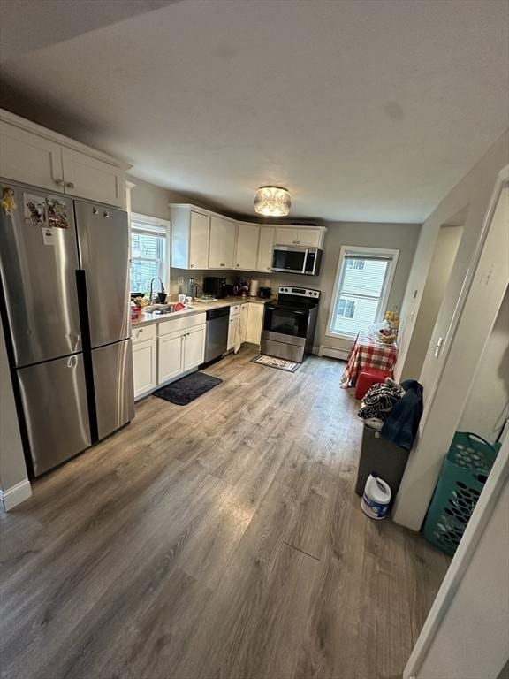21 Sigel St, Worcester, MA 01610 - kitchen with stainless steel appliances, a sink, wood finished floors, light countertops, and white cabinetry