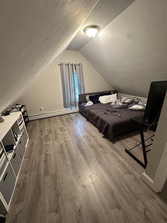 21 Sigel St, Worcester, MA 01610 - bedroom with wood finished floors, a baseboard radiator, vaulted ceiling, and a textured ceiling