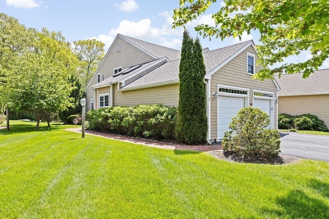 view of home's exterior featuring roof with shingles, a lawn, and asphalt driveway