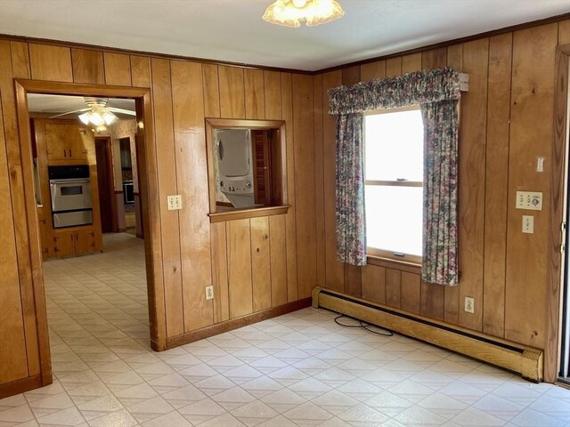 68 Briarbrook Dr, Seekonk, MA 02771 - spare room featuring stacked washing machine and dryer, baseboard heating, wooden walls, a ceiling fan, and baseboards