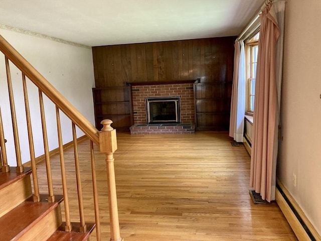 68 Briarbrook Dr, Seekonk, MA 02771 - unfurnished living room featuring baseboard heating, light wood finished floors, stairs, a fireplace, and wooden walls