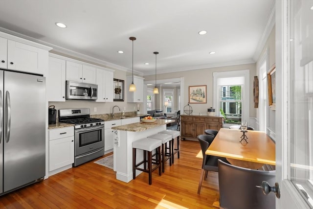 4 Arlington St Unit A, Newburyport, MA 01950 - kitchen with appliances with stainless steel finishes, a breakfast bar, ornamental molding, a sink, and white cabinetry