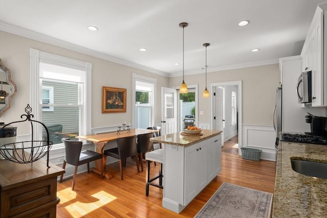 4 Arlington St Unit A, Newburyport, MA 01950 - kitchen with appliances with stainless steel finishes, a center island, white cabinets, light wood-type flooring, and crown molding