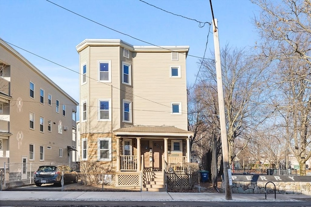 townhome / multi-family property with a porch and a fenced front yard