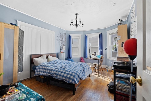 bedroom featuring ornamental molding, a notable chandelier, and hardwood / wood-style floors