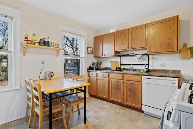 kitchen with dark countertops, a sink, range, dishwasher, and exhaust hood