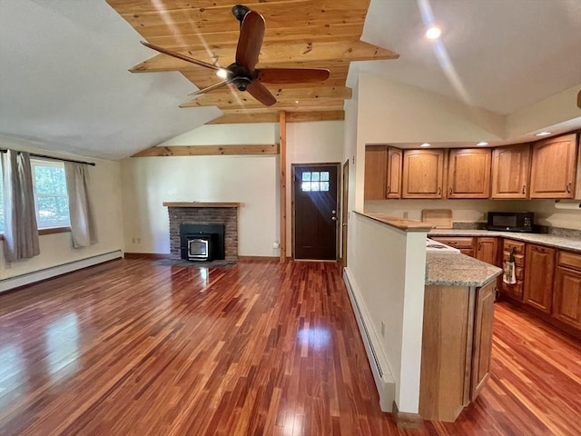 2 Bushy Ln, Rutland, MA 01543 - kitchen with black microwave, a baseboard heating unit, vaulted ceiling, brown cabinets, and wood finished floors