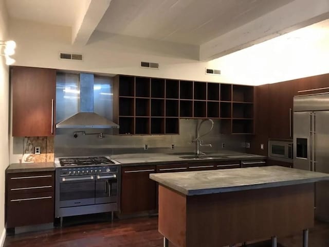 kitchen featuring built in appliances, tasteful backsplash, wall chimney exhaust hood, beamed ceiling, and a center island