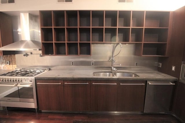 kitchen with appliances with stainless steel finishes, dark brown cabinets, dark hardwood / wood-style flooring, and wall chimney range hood