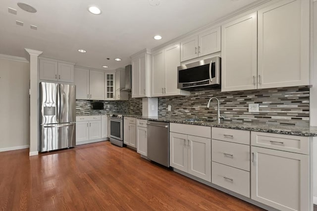 kitchen featuring stainless steel appliances, a sink, recessed lighting, tasteful backsplash, and dark wood-style floors