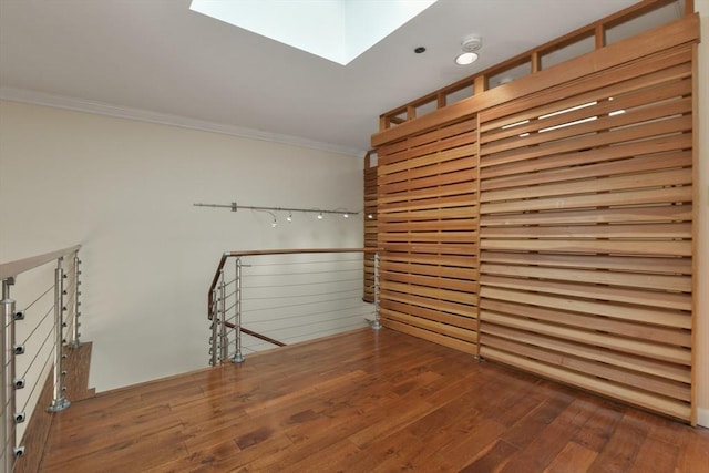 unfurnished room featuring crown molding, hardwood / wood-style floors, and a skylight