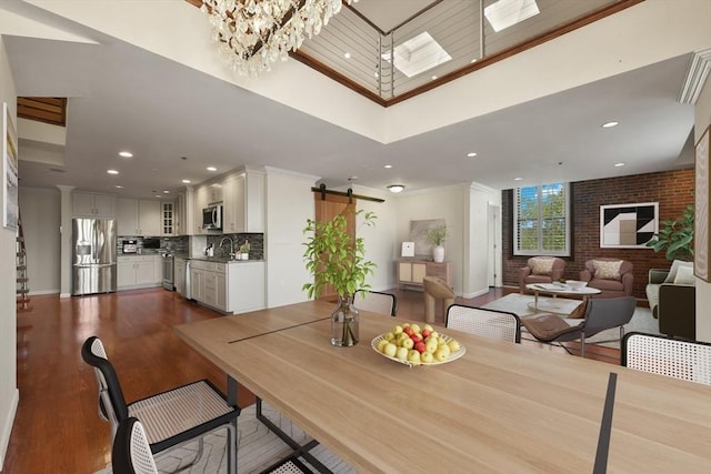 dining area featuring a barn door, ornamental molding, recessed lighting, a chandelier, and dark wood-style flooring