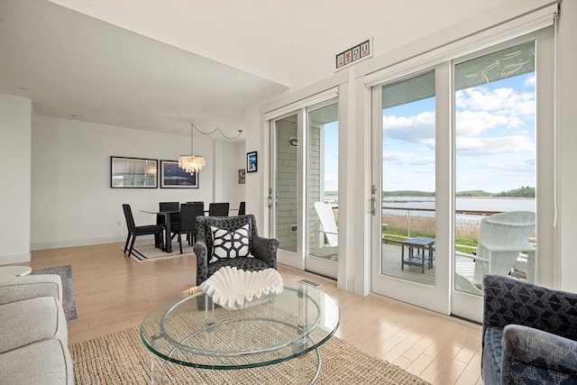 266 Merrimac St Unit F, Newburyport, MA 01950 - living room featuring light wood-type flooring, a water view, a chandelier, and baseboards