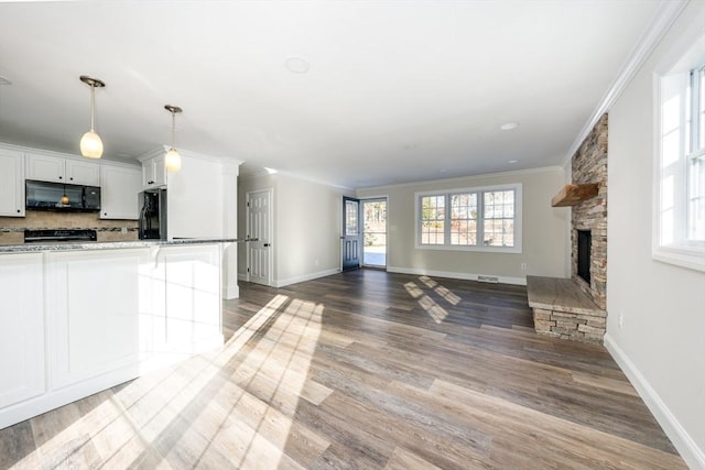 kitchen with a kitchen breakfast bar, a fireplace, white cabinets, black appliances, and ornamental molding